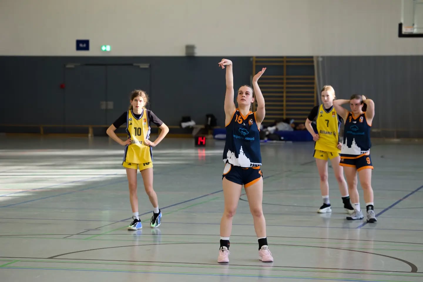 Saisonbericht wu16-1
Die wu16-1 startete hochmotiviert und voller Vorfreude in die OL-Saison 2025/26. Von Beginn an war klar, dass uns ein paar u14erinnen helfen sollten, da der 2011er Jahrgang mittlerweile auf zwei letzte Urgesteine zusammen geschrumpft war. Wie sehr wir auf die wu14 angewiesen sein würden, konnten wir im September noch nicht ahnen. Mit 12 Teams in der Liga hatten wir einen eng getakteten Spielplan vor uns. Jedoch zwangen uns mehrere Verletzungen dazu, immer mehr Spiele nach hinten zu schieben. So hatten wir bis Ende des Jahres einen sehr zerrupften Spielplan und kamen nur schwer ins Rollen. Gegen Gegnerinnen aus der unteren Tabellenhälfte fiel das nicht so sehr ins Gewicht und oft bestand der Kader aus mehr u14ern als u16er. Spielerinnen, die ursprünglich (noch) gar nicht für die OL eingeplant waren, nutzten ihre Chance, und erspielten sich so einen festen Platz im Kader.
Ausgerechnet gegen ALBA 2 im Dezember hatten wir vorher 3 Wochen Pause und performten nicht gerade eingespielt. Das Ergebnis: die erste Niederlage der Saison.
Am Ende gingen wir nach 22 Spielen mit 5 Niederlagen raus, wobei davon nur 3 gespielt wurden. Leider mussten wir nämlich beide Spiele gegen ALBA 1 immer wieder schieben und am Ende absagen, was uns zusätzlich Wertungs-Minuspunkte einbrachte. Nichtsdestotrotz war der Abstand zu Platz 5 groß genug, sodass wir uns für das Top4 qualifizierten. Eine neue Regelung führte dazu, dass wir keine Aushilfen aus der u14 für diesen wichtigen Saisonhöhepunkt bekamen, und das obwohl diese Spielerinnen teilweise maßgeblich für den Saisonverlauf verantwortlich waren. Eine weitere Verletzung reduzierte unseren Kader auf 8 Spielerinnen, wovon drei bisher noch gar nicht oder nur vereinzelt Spiele in der Saison für die OL absolvierten.
Entsprechend herausfordernd gestaltete sich das Wochenende für uns. Der 4. Platz war folgerichtig, aber nichtsdestotrotz ein starkes Ergebnis für eine Saison, die so gar nicht nach Plan verlief. Umso stolzer sind wir auf alles, was wir erreicht haben. Für die wu16-1 spielten
Luise, Leo, Pheline, Mette, Paula, Malin, Karo, Lotta, Luzie, Greta, Tildi, Lori, Jara, Mathi, Lotti, Hella, Maggie, Amelie, Loubna