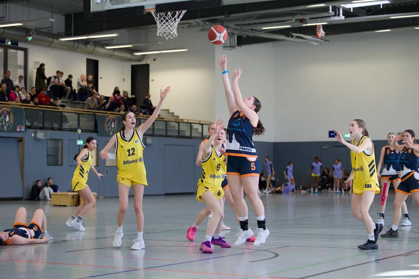 Saisonbericht wu16-1
Die wu16-1 startete hochmotiviert und voller Vorfreude in die OL-Saison 2025/26. Von Beginn an war klar, dass uns ein paar u14erinnen helfen sollten, da der 2011er Jahrgang mittlerweile auf zwei letzte Urgesteine zusammen geschrumpft war. Wie sehr wir auf die wu14 angewiesen sein würden, konnten wir im September noch nicht ahnen. Mit 12 Teams in der Liga hatten wir einen eng getakteten Spielplan vor uns. Jedoch zwangen uns mehrere Verletzungen dazu, immer mehr Spiele nach hinten zu schieben. So hatten wir bis Ende des Jahres einen sehr zerrupften Spielplan und kamen nur schwer ins Rollen. Gegen Gegnerinnen aus der unteren Tabellenhälfte fiel das nicht so sehr ins Gewicht und oft bestand der Kader aus mehr u14ern als u16er. Spielerinnen, die ursprünglich (noch) gar nicht für die OL eingeplant waren, nutzten ihre Chance, und erspielten sich so einen festen Platz im Kader.
Ausgerechnet gegen ALBA 2 im Dezember hatten wir vorher 3 Wochen Pause und performten nicht gerade eingespielt. Das Ergebnis: die erste Niederlage der Saison.
Am Ende gingen wir nach 22 Spielen mit 5 Niederlagen raus, wobei davon nur 3 gespielt wurden. Leider mussten wir nämlich beide Spiele gegen ALBA 1 immer wieder schieben und am Ende absagen, was uns zusätzlich Wertungs-Minuspunkte einbrachte. Nichtsdestotrotz war der Abstand zu Platz 5 groß genug, sodass wir uns für das Top4 qualifizierten. Eine neue Regelung führte dazu, dass wir keine Aushilfen aus der u14 für diesen wichtigen Saisonhöhepunkt bekamen, und das obwohl diese Spielerinnen teilweise maßgeblich für den Saisonverlauf verantwortlich waren. Eine weitere Verletzung reduzierte unseren Kader auf 8 Spielerinnen, wovon drei bisher noch gar nicht oder nur vereinzelt Spiele in der Saison für die OL absolvierten.
Entsprechend herausfordernd gestaltete sich das Wochenende für uns. Der 4. Platz war folgerichtig, aber nichtsdestotrotz ein starkes Ergebnis für eine Saison, die so gar nicht nach Plan verlief. Umso stolzer sind wir auf alles, was wir erreicht haben. Für die wu16-1 spielten
Luise, Leo, Pheline, Mette, Paula, Malin, Karo, Lotta, Luzie, Greta, Tildi, Lori, Jara, Mathi, Lotti, Hella, Maggie, Amelie, Loubna