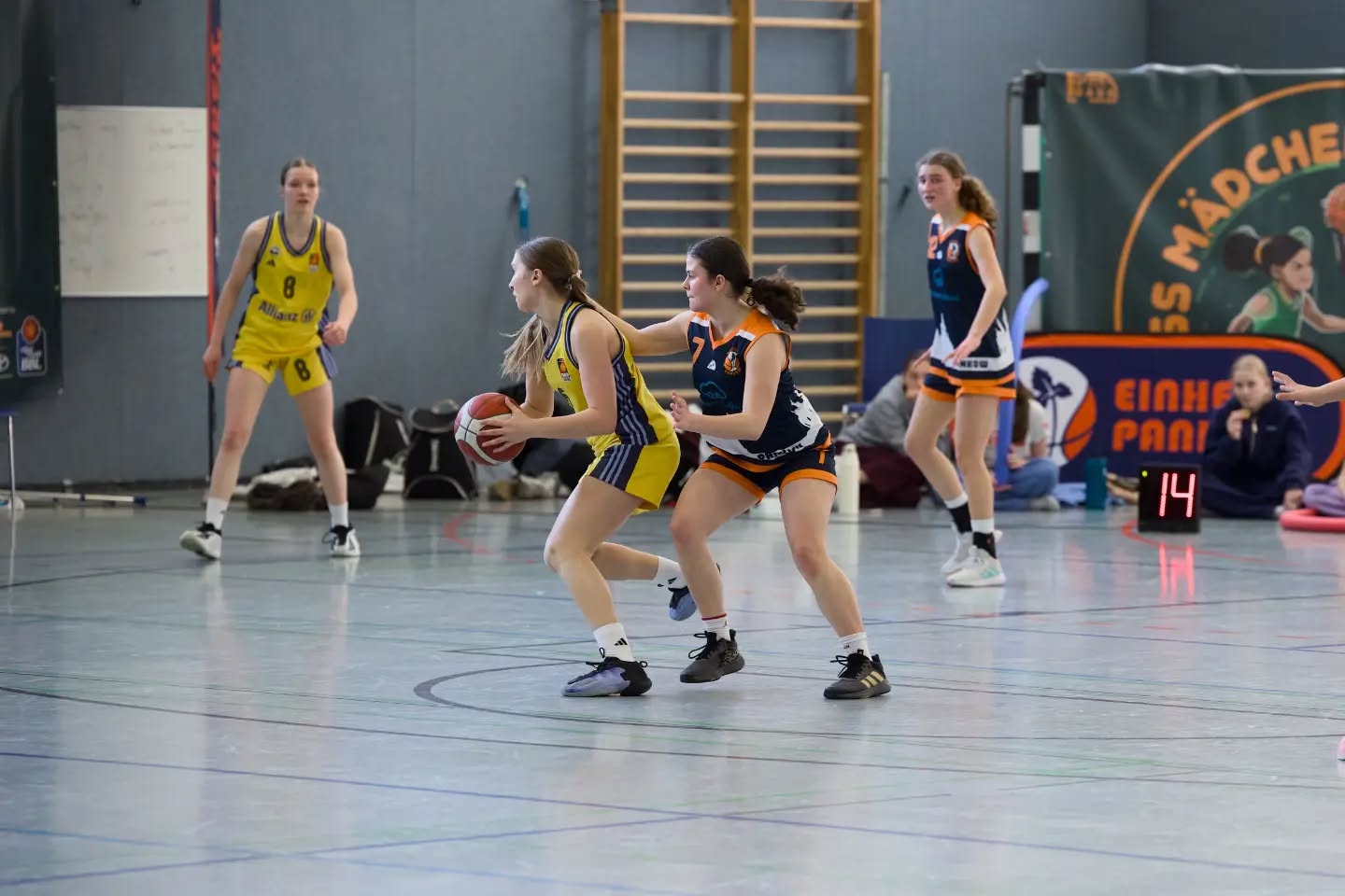 Saisonbericht wu16-1
Die wu16-1 startete hochmotiviert und voller Vorfreude in die OL-Saison 2025/26. Von Beginn an war klar, dass uns ein paar u14erinnen helfen sollten, da der 2011er Jahrgang mittlerweile auf zwei letzte Urgesteine zusammen geschrumpft war. Wie sehr wir auf die wu14 angewiesen sein würden, konnten wir im September noch nicht ahnen. Mit 12 Teams in der Liga hatten wir einen eng getakteten Spielplan vor uns. Jedoch zwangen uns mehrere Verletzungen dazu, immer mehr Spiele nach hinten zu schieben. So hatten wir bis Ende des Jahres einen sehr zerrupften Spielplan und kamen nur schwer ins Rollen. Gegen Gegnerinnen aus der unteren Tabellenhälfte fiel das nicht so sehr ins Gewicht und oft bestand der Kader aus mehr u14ern als u16er. Spielerinnen, die ursprünglich (noch) gar nicht für die OL eingeplant waren, nutzten ihre Chance, und erspielten sich so einen festen Platz im Kader.
Ausgerechnet gegen ALBA 2 im Dezember hatten wir vorher 3 Wochen Pause und performten nicht gerade eingespielt. Das Ergebnis: die erste Niederlage der Saison.
Am Ende gingen wir nach 22 Spielen mit 5 Niederlagen raus, wobei davon nur 3 gespielt wurden. Leider mussten wir nämlich beide Spiele gegen ALBA 1 immer wieder schieben und am Ende absagen, was uns zusätzlich Wertungs-Minuspunkte einbrachte. Nichtsdestotrotz war der Abstand zu Platz 5 groß genug, sodass wir uns für das Top4 qualifizierten. Eine neue Regelung führte dazu, dass wir keine Aushilfen aus der u14 für diesen wichtigen Saisonhöhepunkt bekamen, und das obwohl diese Spielerinnen teilweise maßgeblich für den Saisonverlauf verantwortlich waren. Eine weitere Verletzung reduzierte unseren Kader auf 8 Spielerinnen, wovon drei bisher noch gar nicht oder nur vereinzelt Spiele in der Saison für die OL absolvierten.
Entsprechend herausfordernd gestaltete sich das Wochenende für uns. Der 4. Platz war folgerichtig, aber nichtsdestotrotz ein starkes Ergebnis für eine Saison, die so gar nicht nach Plan verlief. Umso stolzer sind wir auf alles, was wir erreicht haben. Für die wu16-1 spielten
Luise, Leo, Pheline, Mette, Paula, Malin, Karo, Lotta, Luzie, Greta, Tildi, Lori, Jara, Mathi, Lotti, Hella, Maggie, Amelie, Loubna